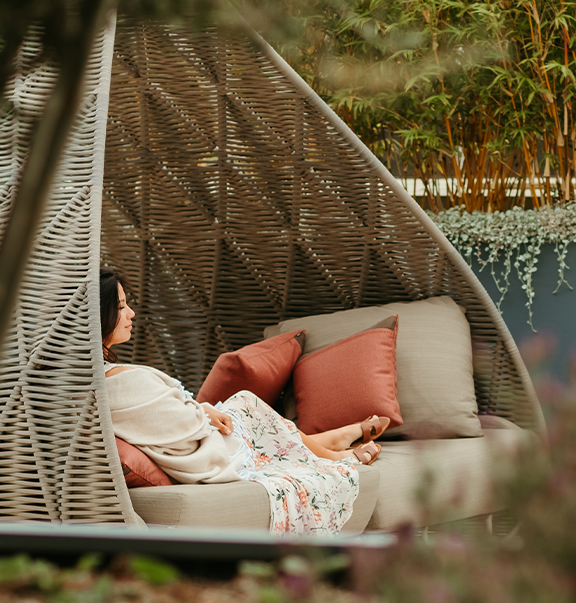 a person lying in a large outdoor couch in a garden