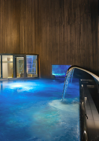 A waterfall over the dim lit indoor pool.