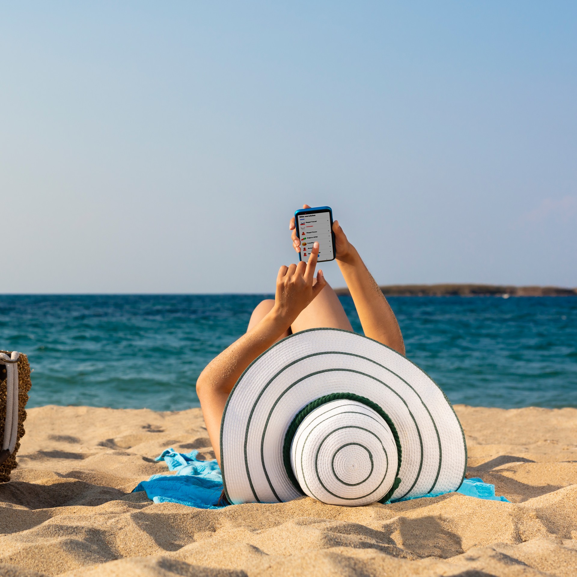 a person lying on the beach with a hat and a phone