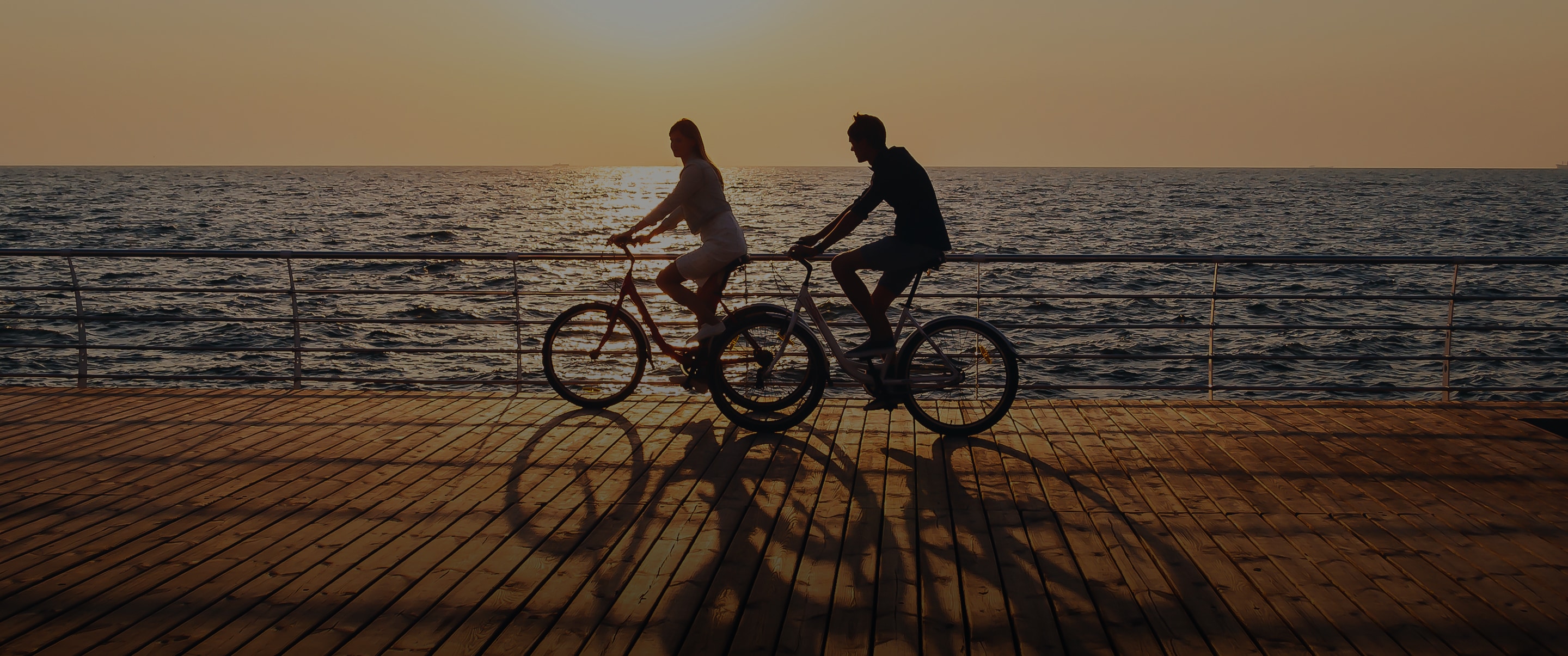 a man and woman riding bicycles on a boardwalk