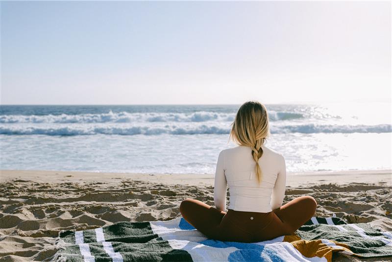 a woman sitting on a blanket on a beach