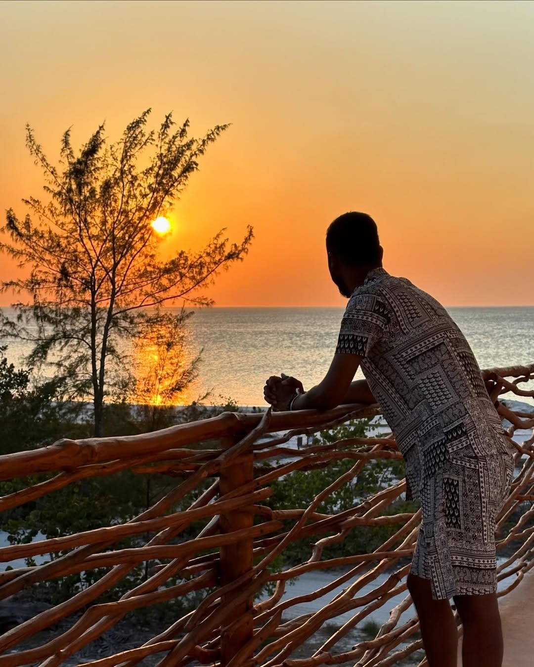 Guest watching sunset over the ocean from a wooden terrace at Mystique Holbox.