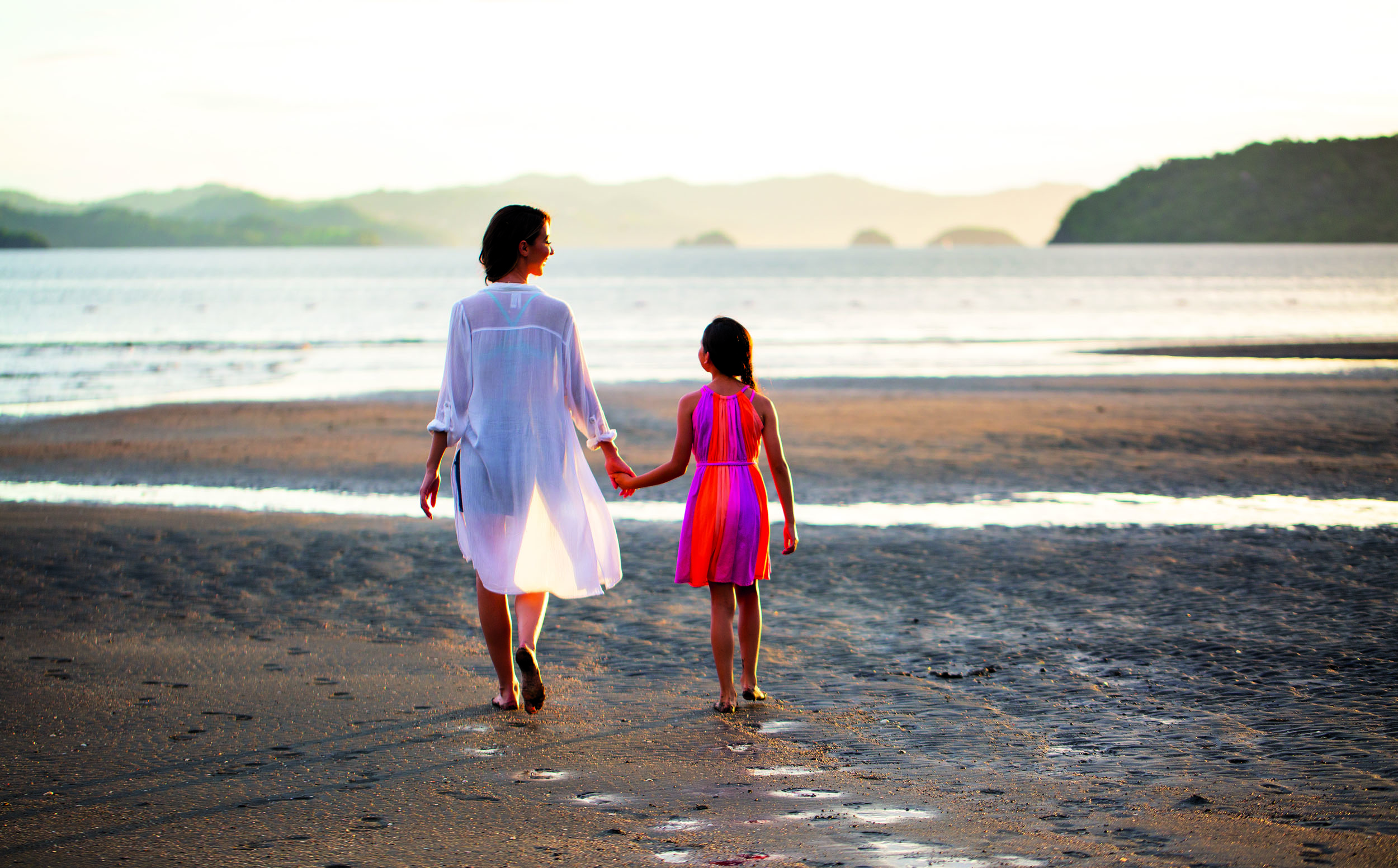 a woman and a child walking on a beach