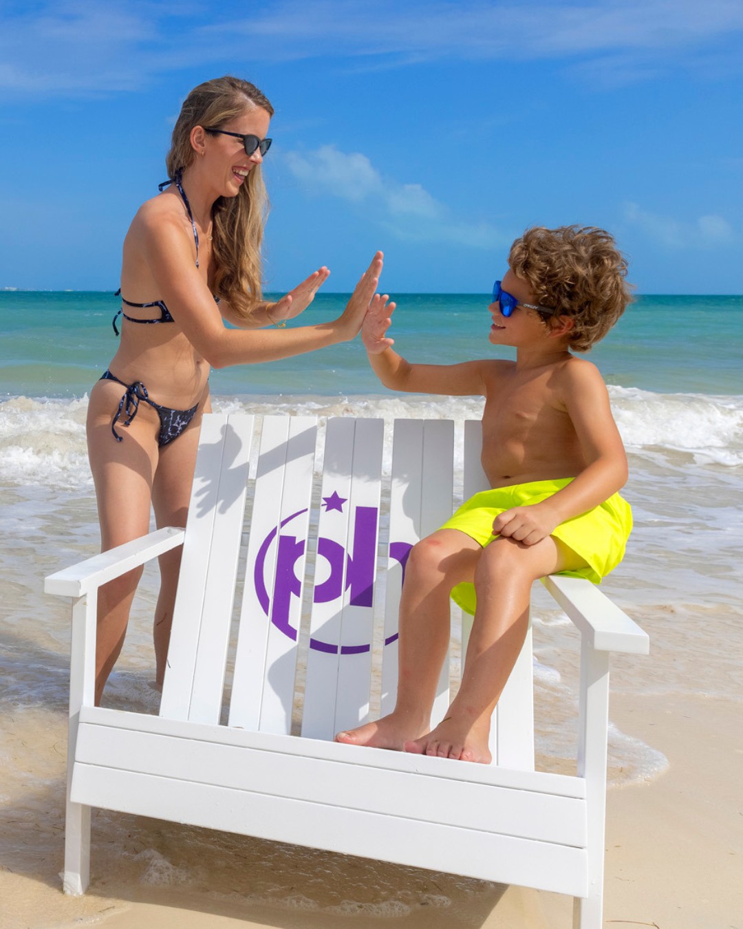 a woman and boy in a garment giving high five to each other on a beach