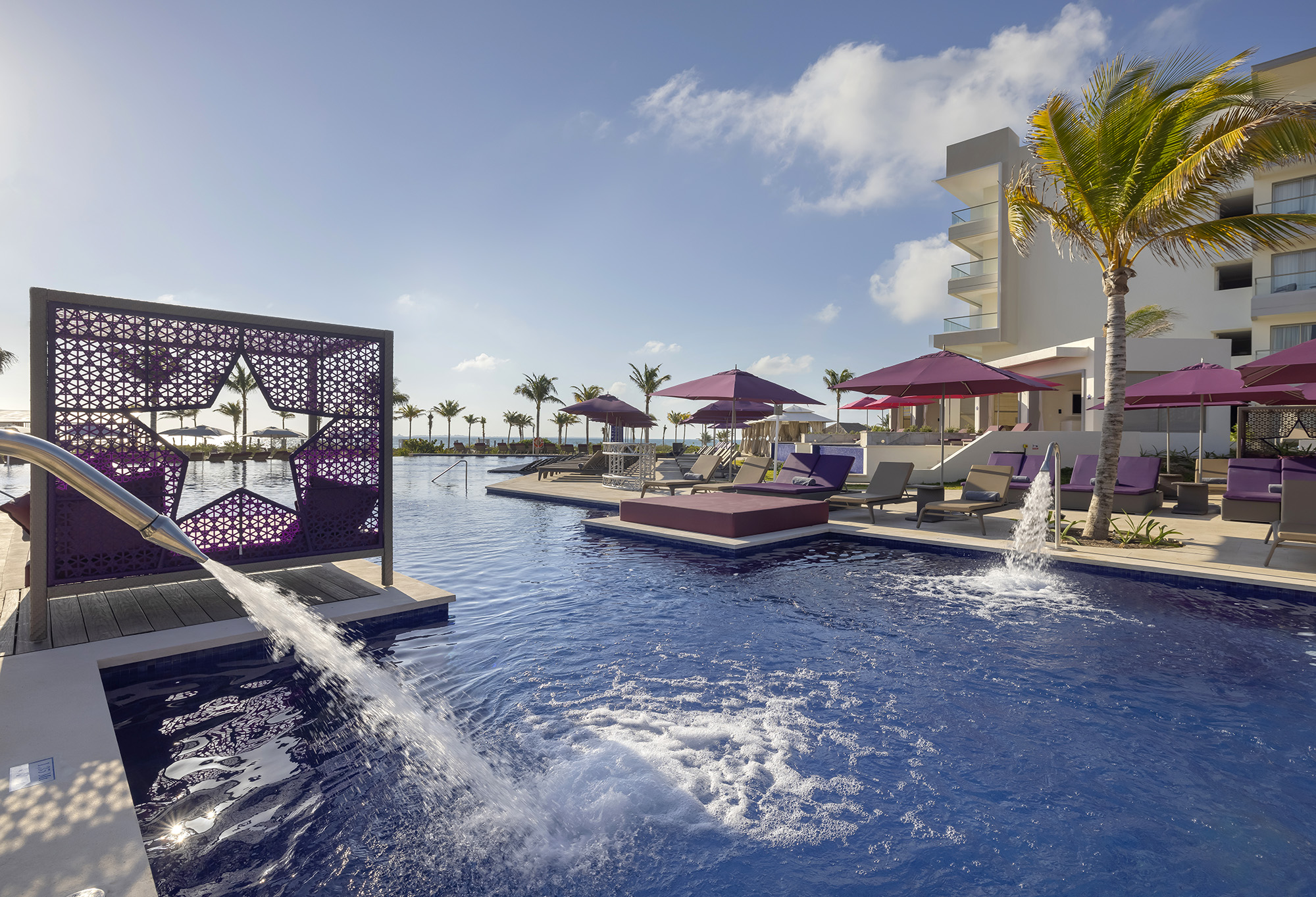 a pool with a fountain and umbrellas