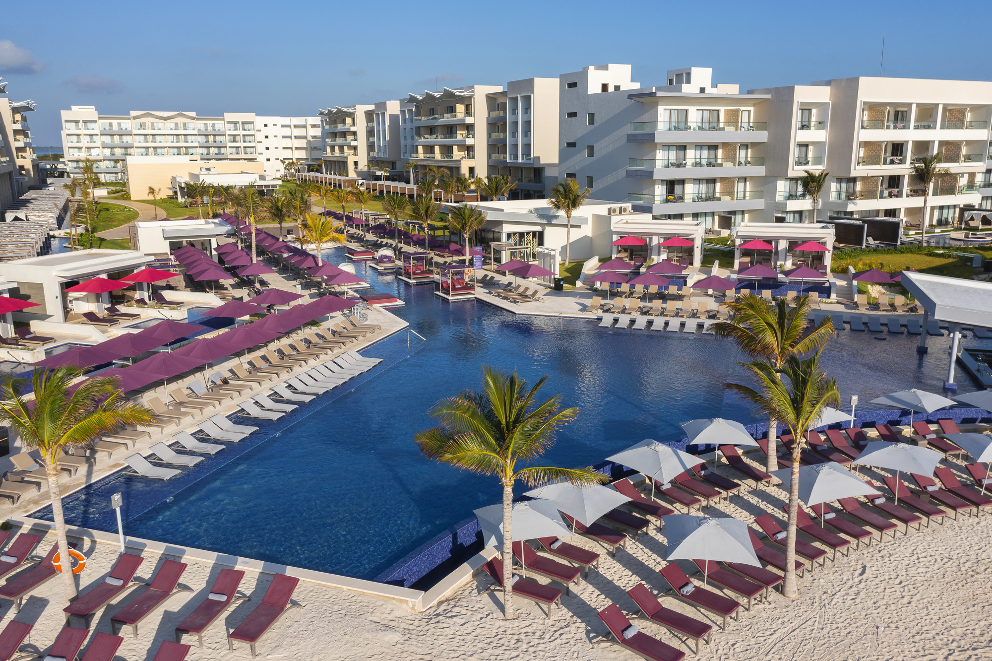 a pool with umbrellas and lounge chairs on a beach