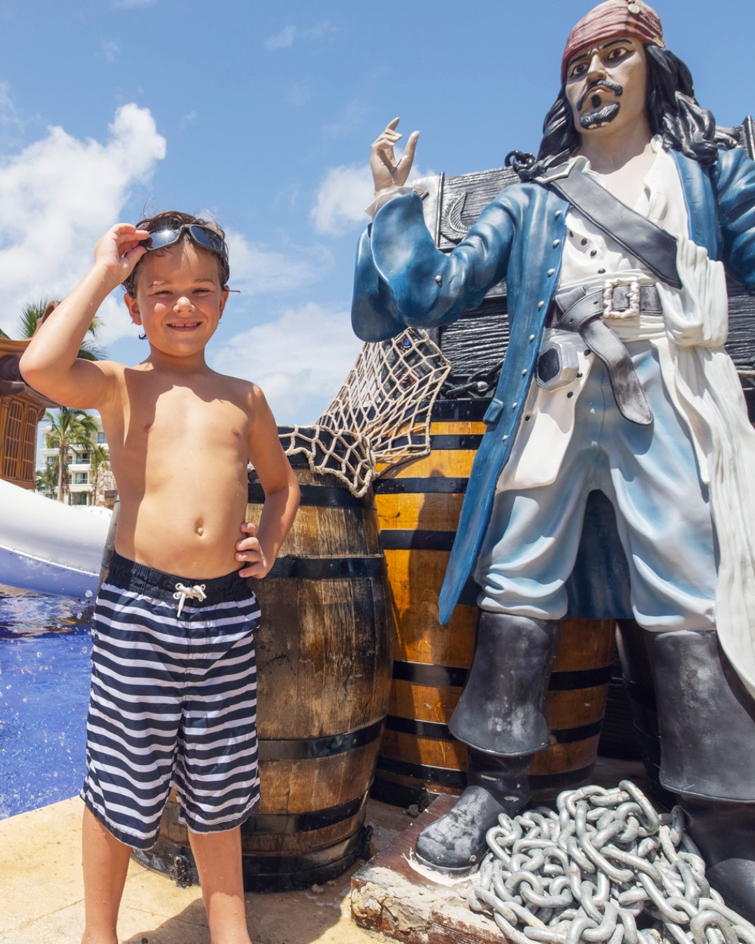 a boy standing in front of a statue of a pirate