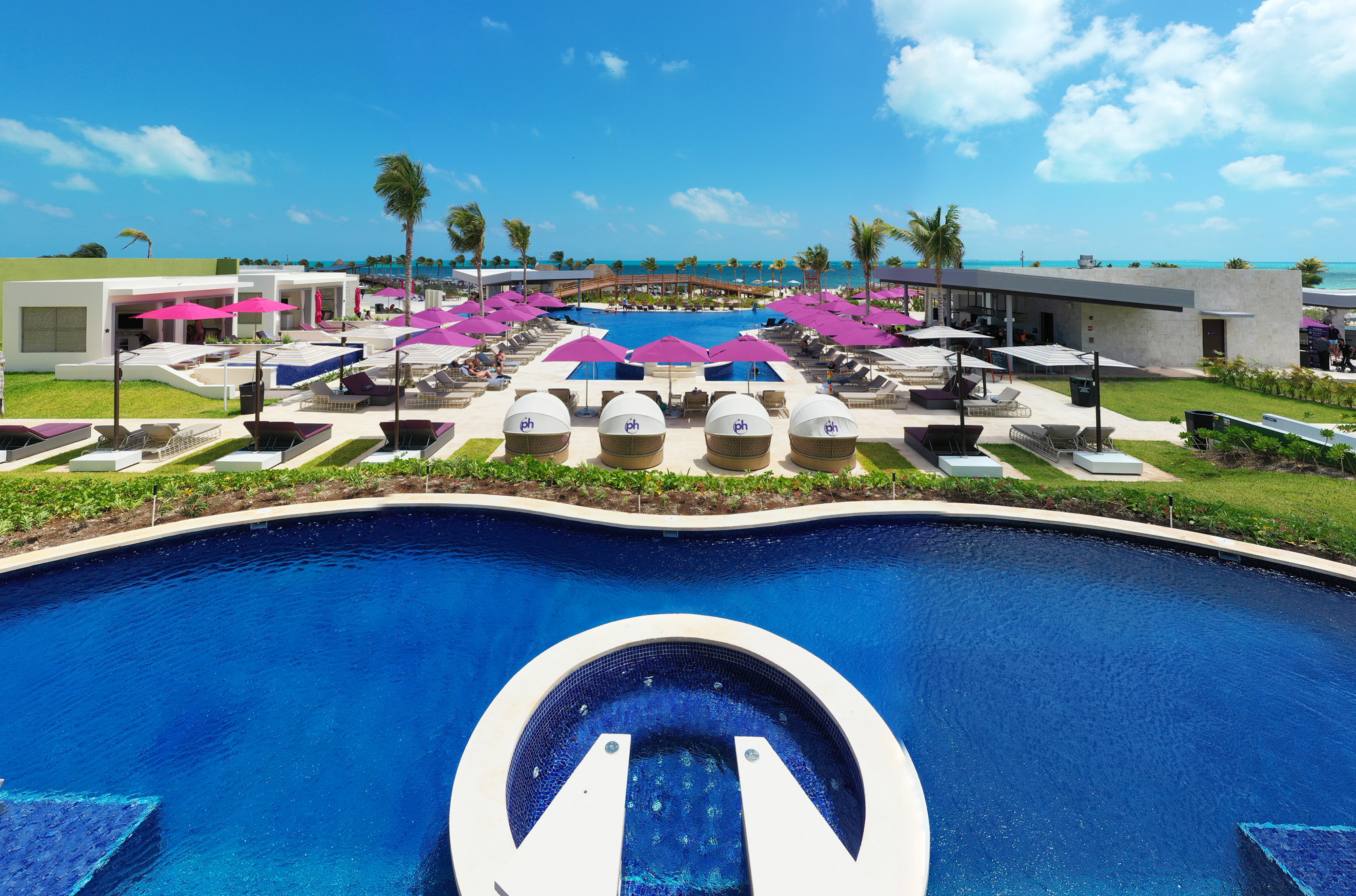 a pool with umbrellas and chairs and a beach
