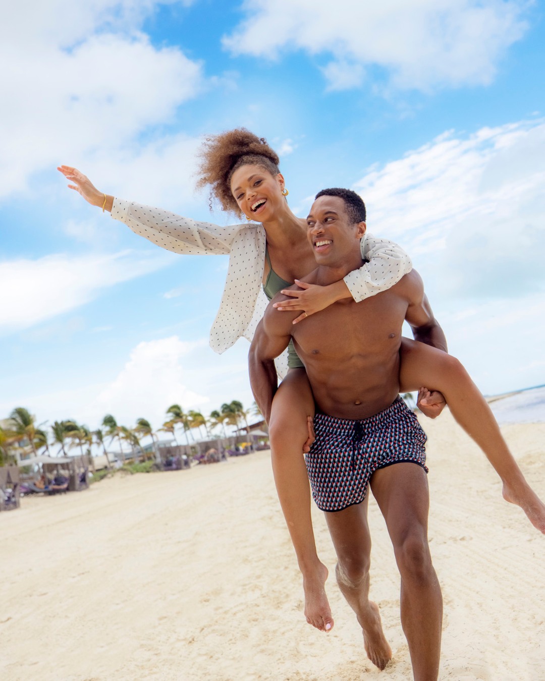 a man carrying a woman on his back on a beach