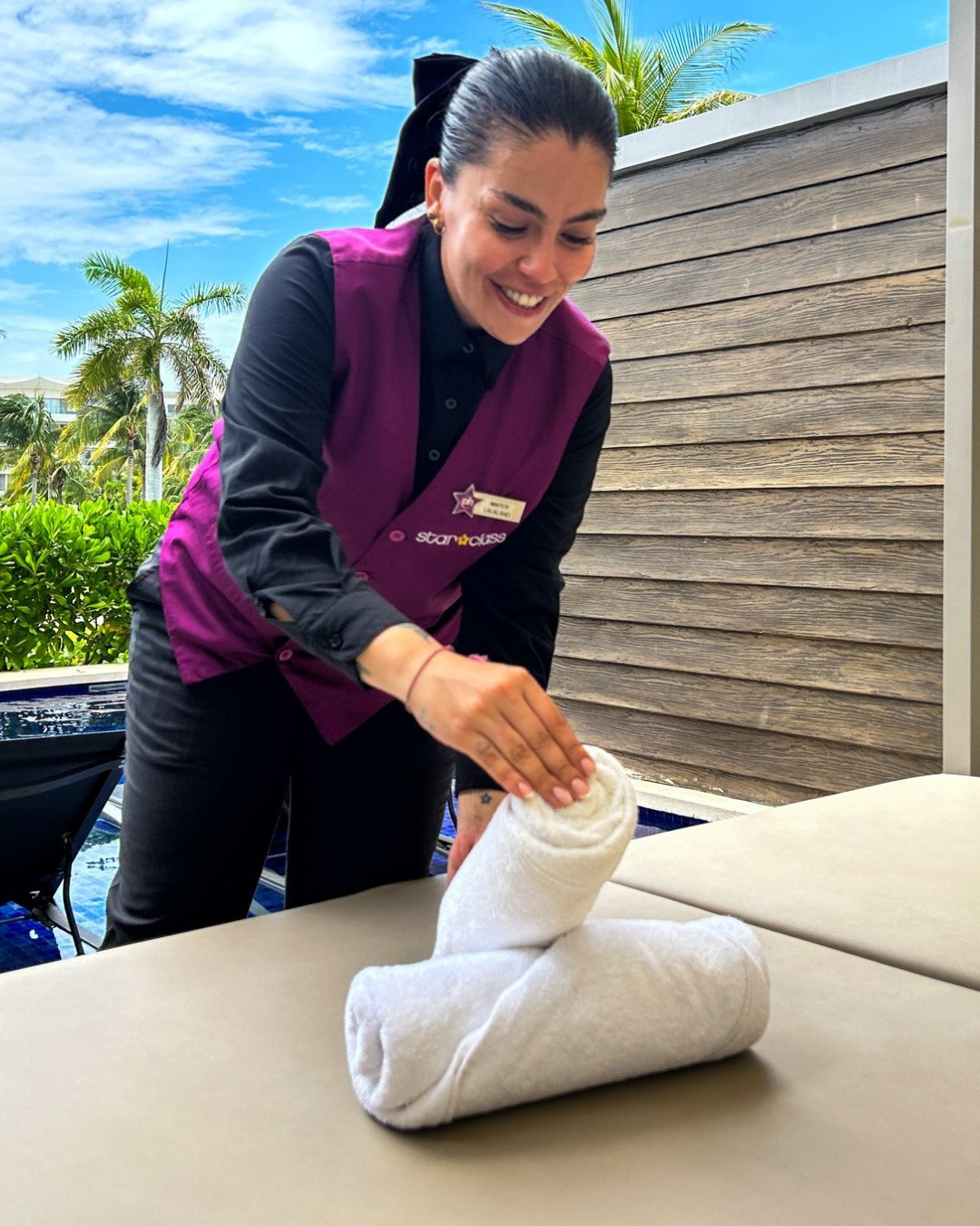a woman in a purple uniform folding towels