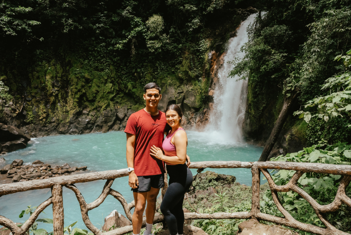 a man and woman posing for a picture in front of a waterfall