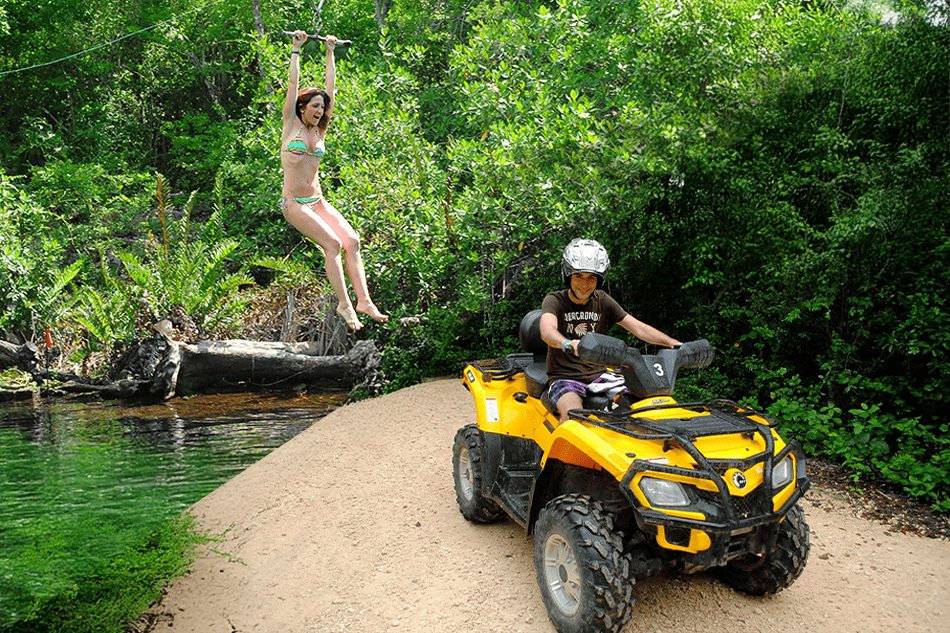 a woman in a garment jumping off a yellow atv by a river