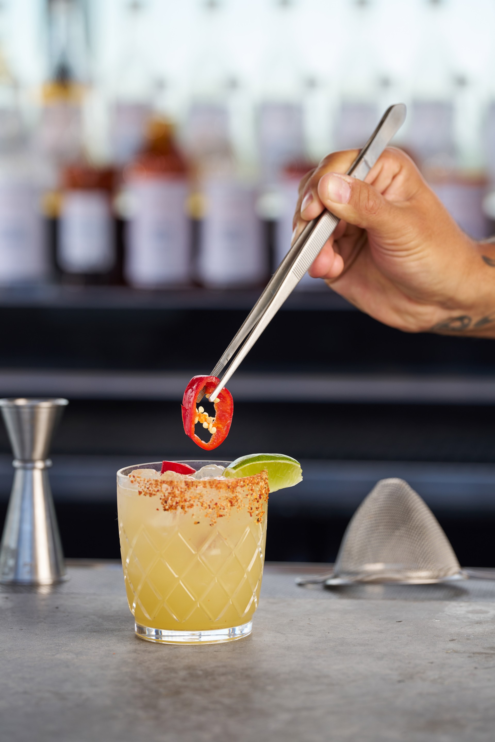 a person holding a tweezers over a drink main