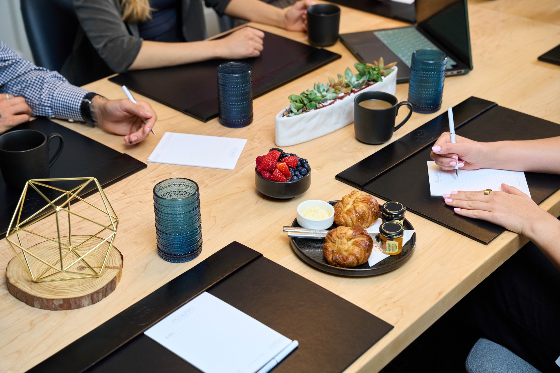 a group of people sitting around a table with laptops and papers main