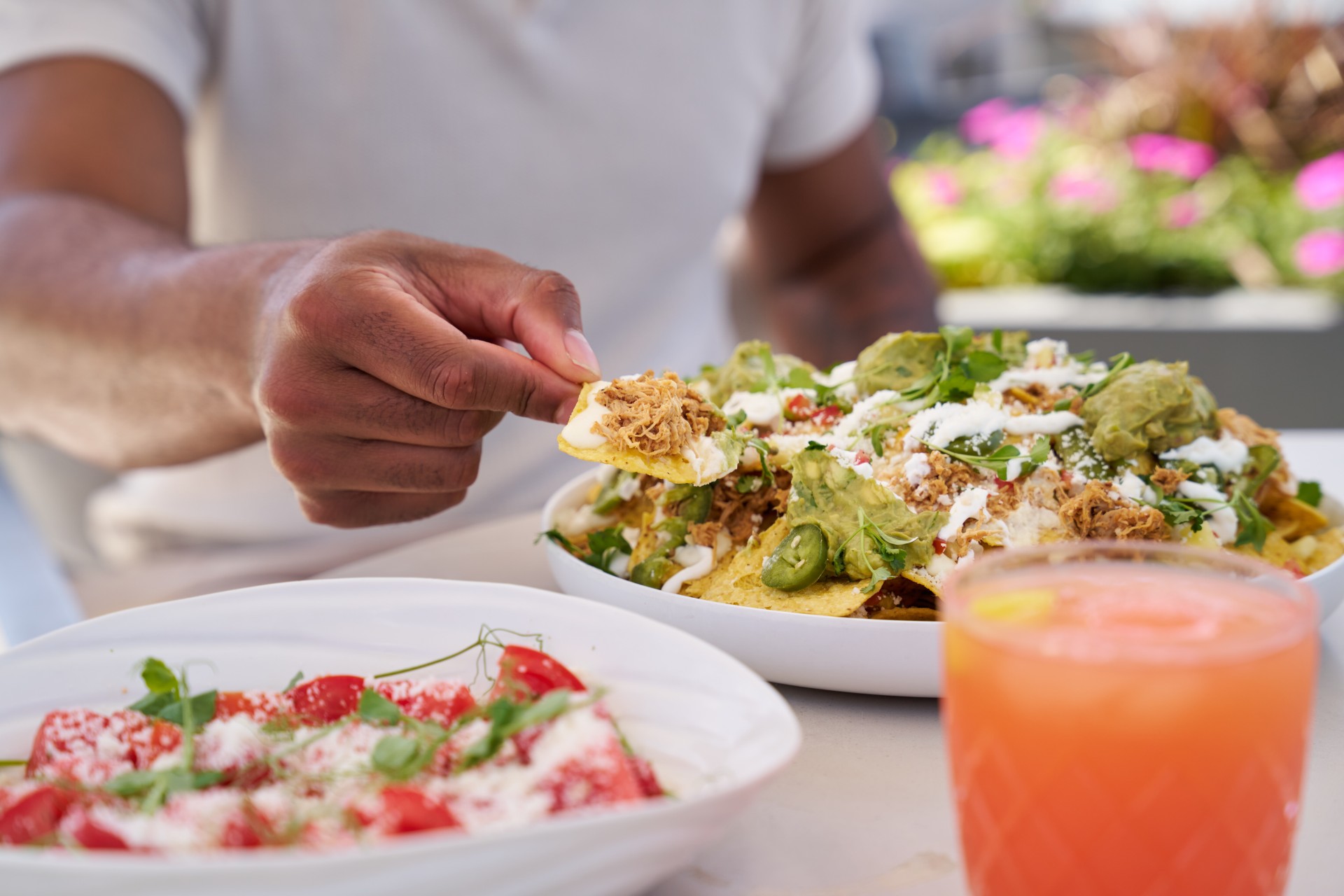a person holding a chip in a bowl of nachos main
