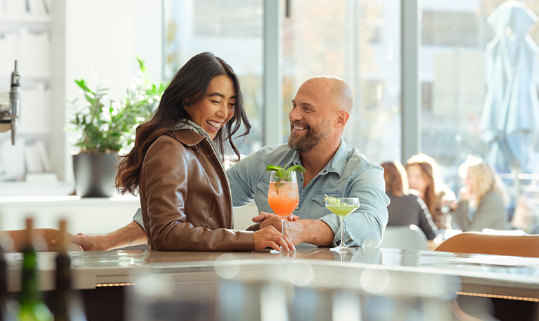 a man and woman sitting at a bar with drinks