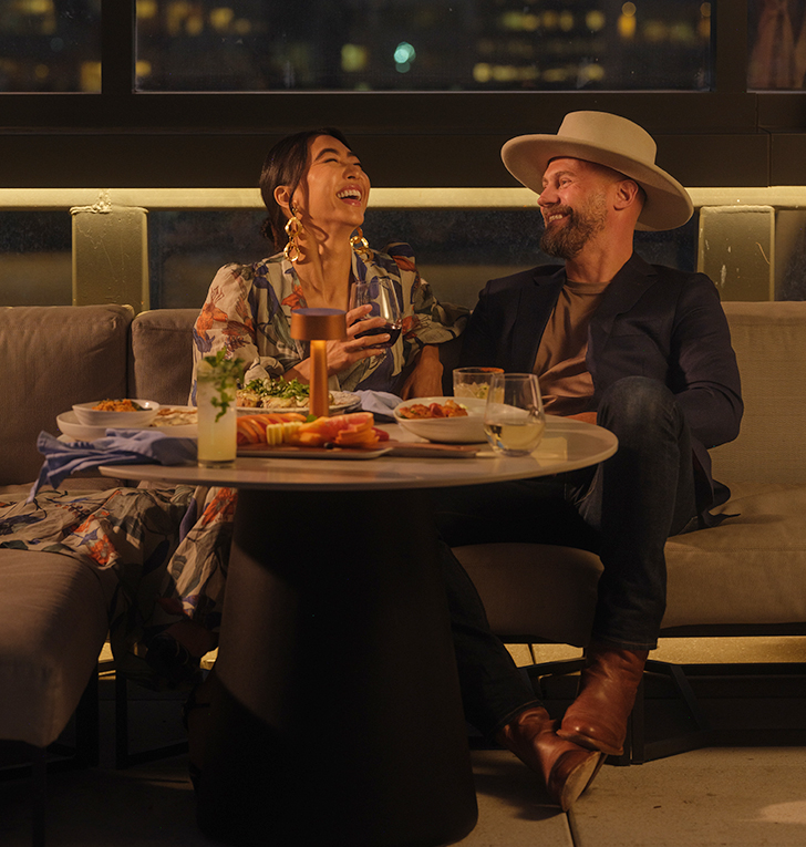 a man and woman sitting at a table with food and drinks