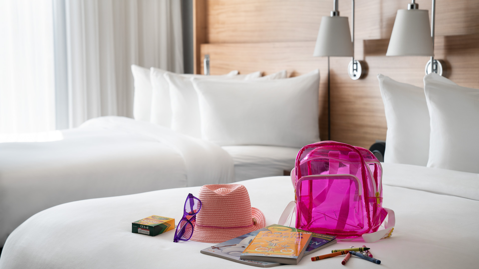 a pink backpack and hat on a bed