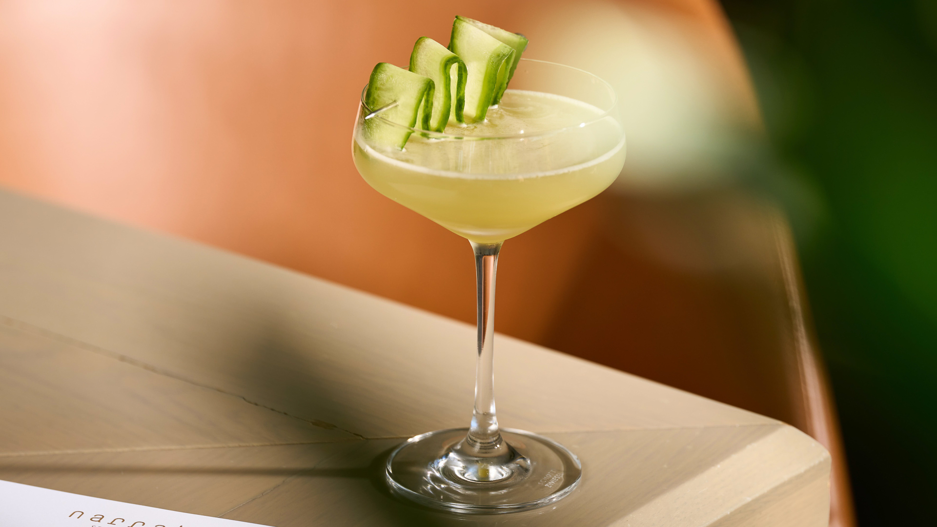 a glass with a drink and a cucumber garnish
