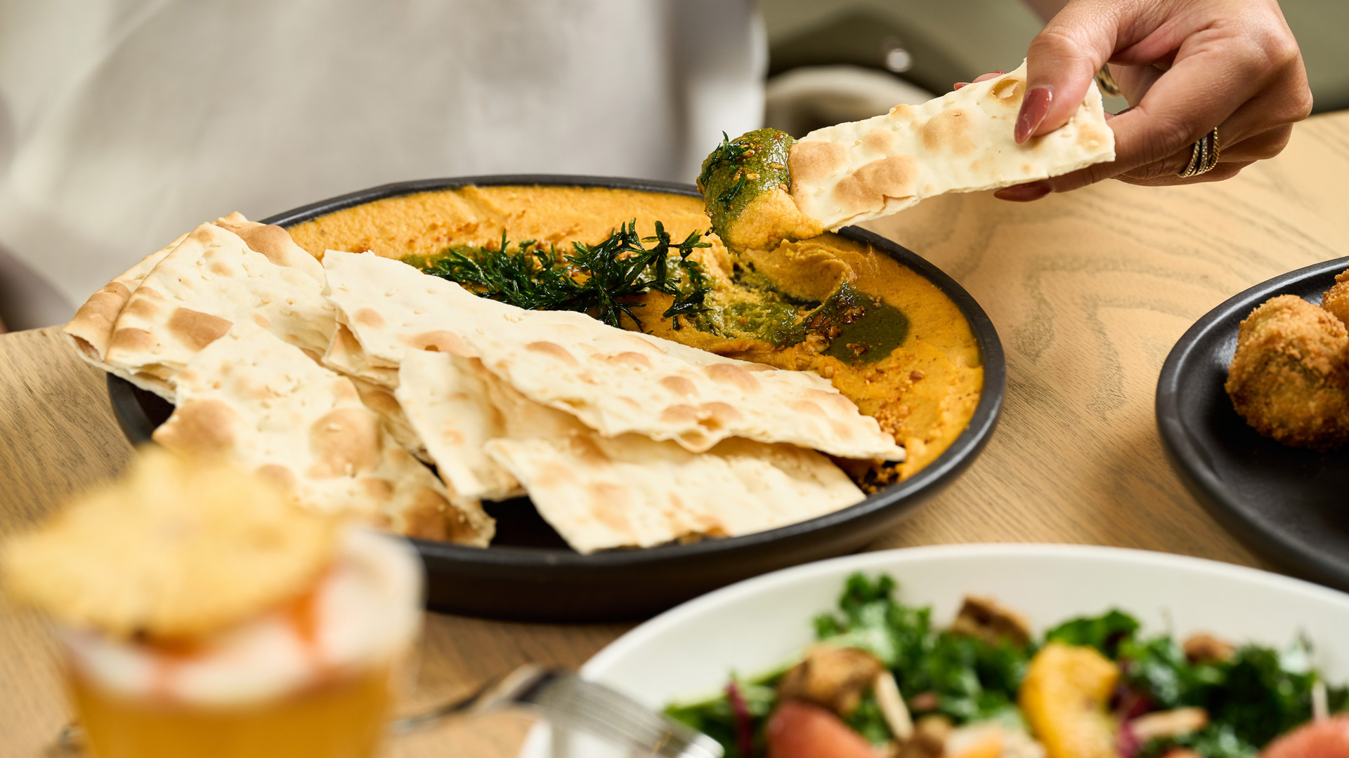 a person dipping a dip into a bowl of food