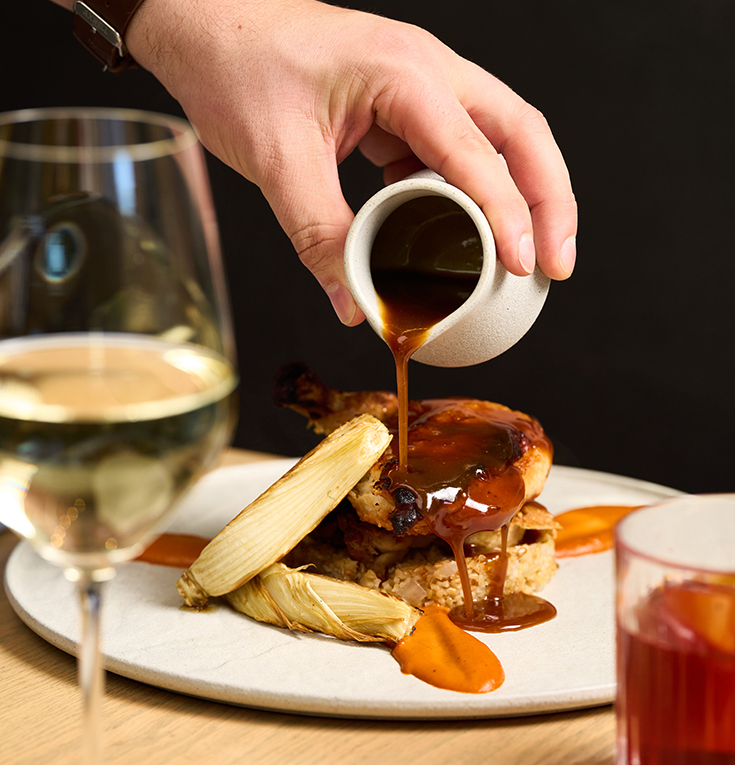 a person pouring gravy on a plate of food