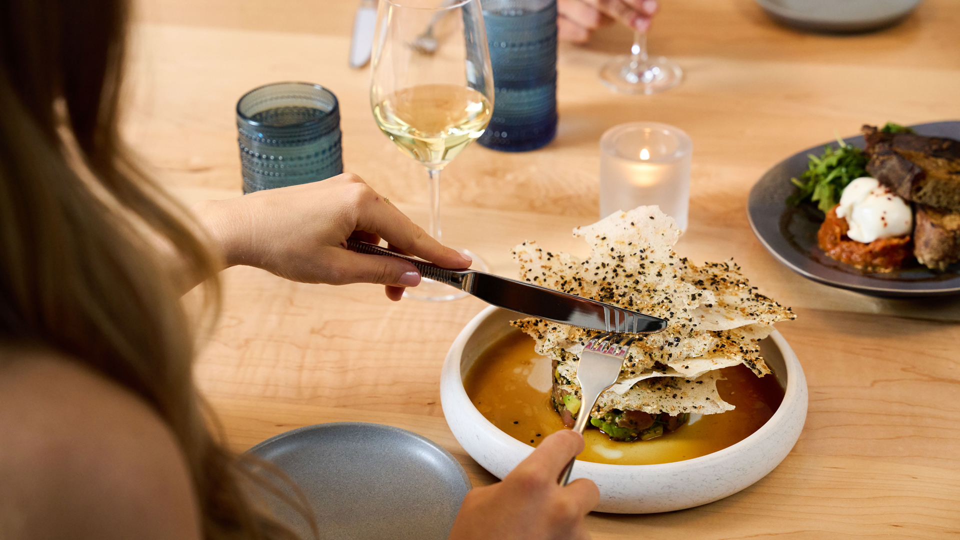 a person eating food with a knife and fork main