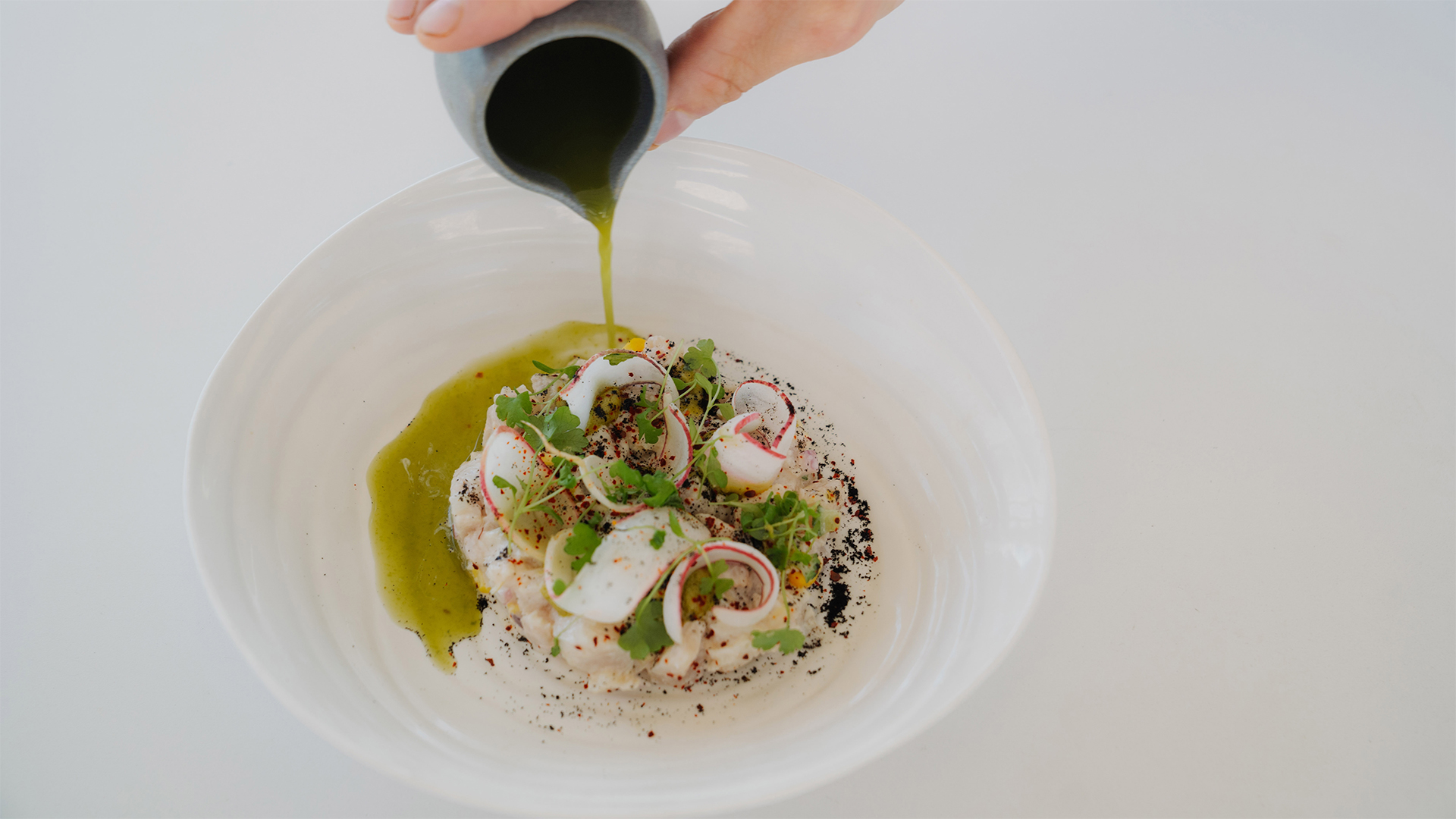 a person pouring a sauce onto a bowl of food main