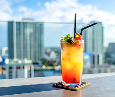 a glass of colorful drink with straws on a table