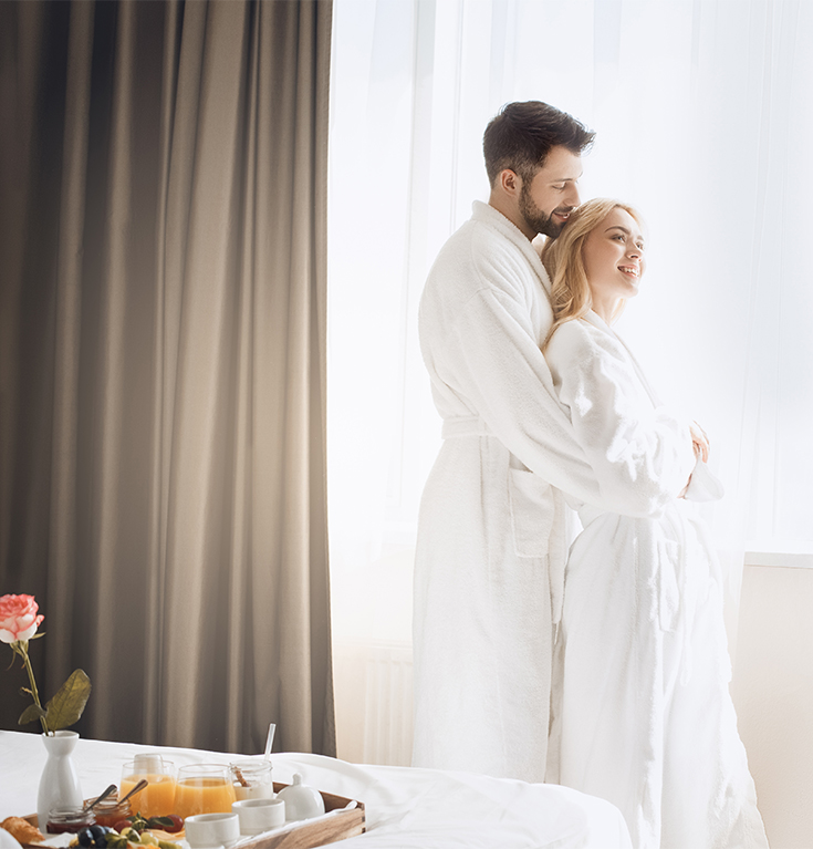 a man and woman in white robes hugging in front of a window