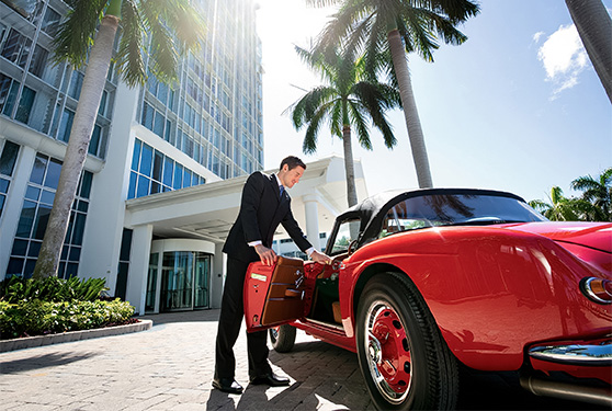 a man opening a suitcase of a red car