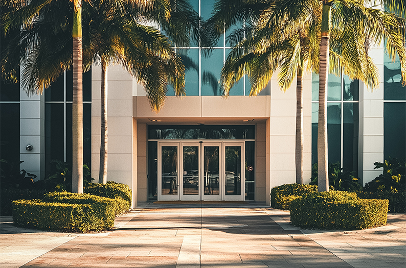 a building with glass doors and palm trees