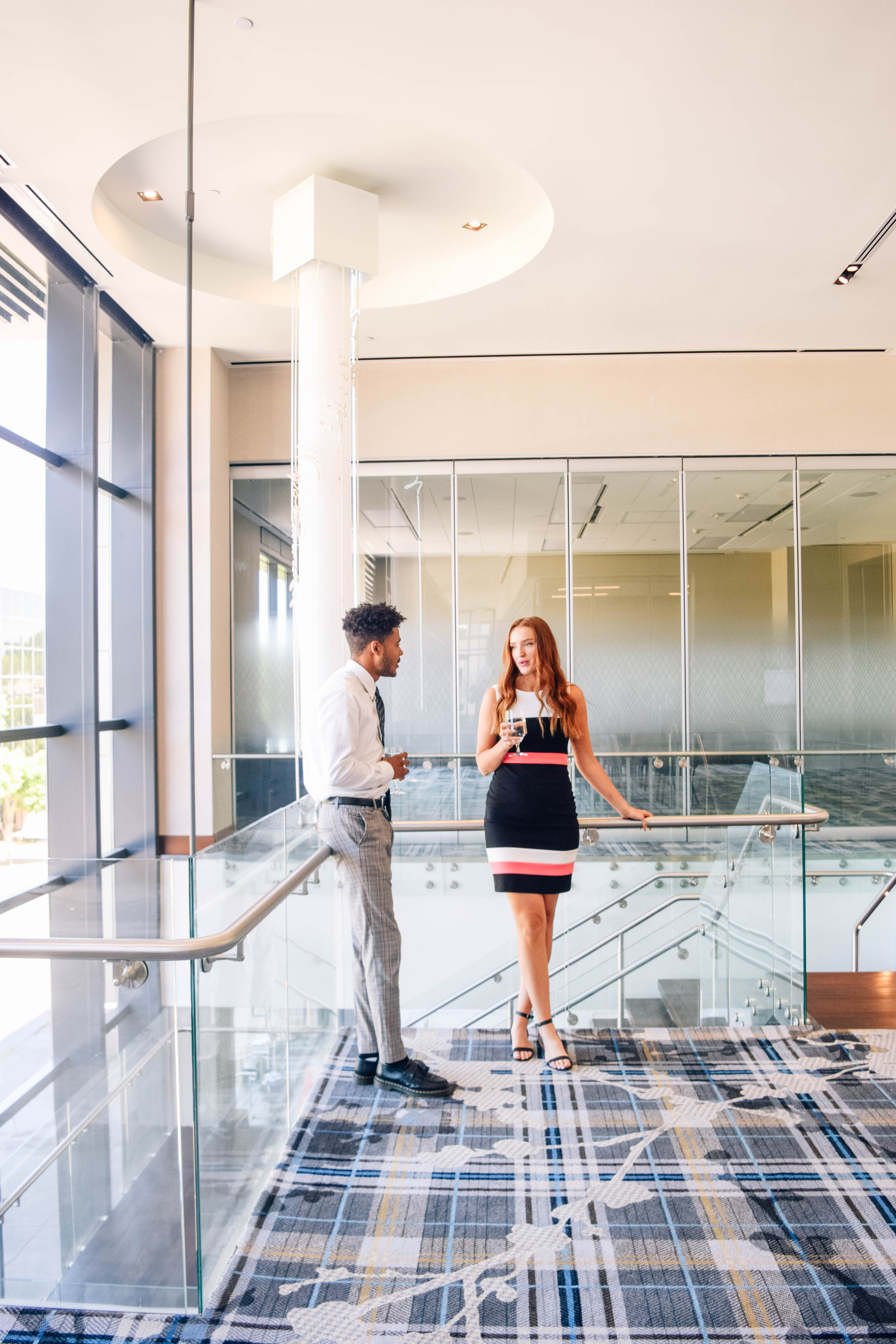 a man and woman standing in a room with glass walls and railings main