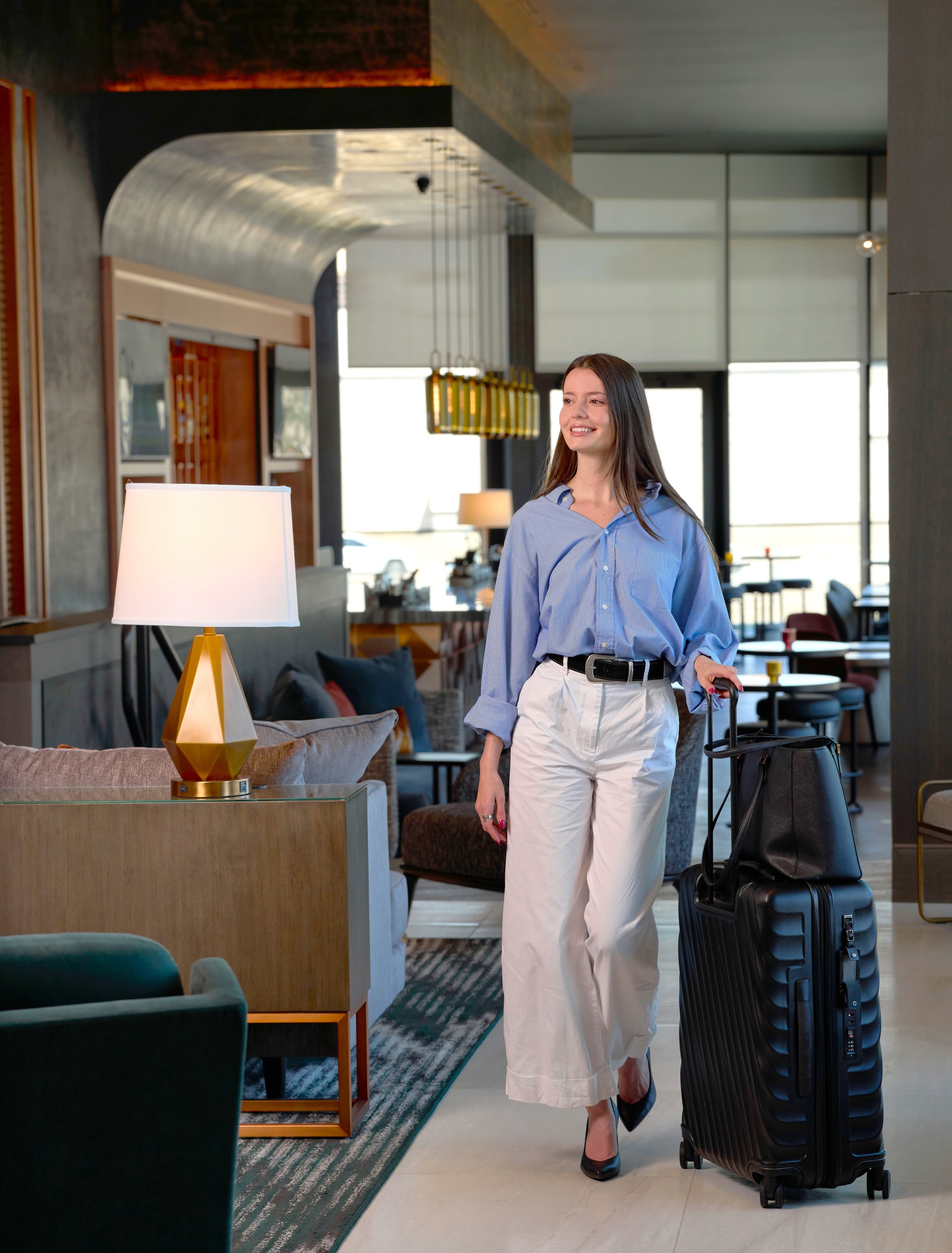a woman walking with luggage in a hotel lobby