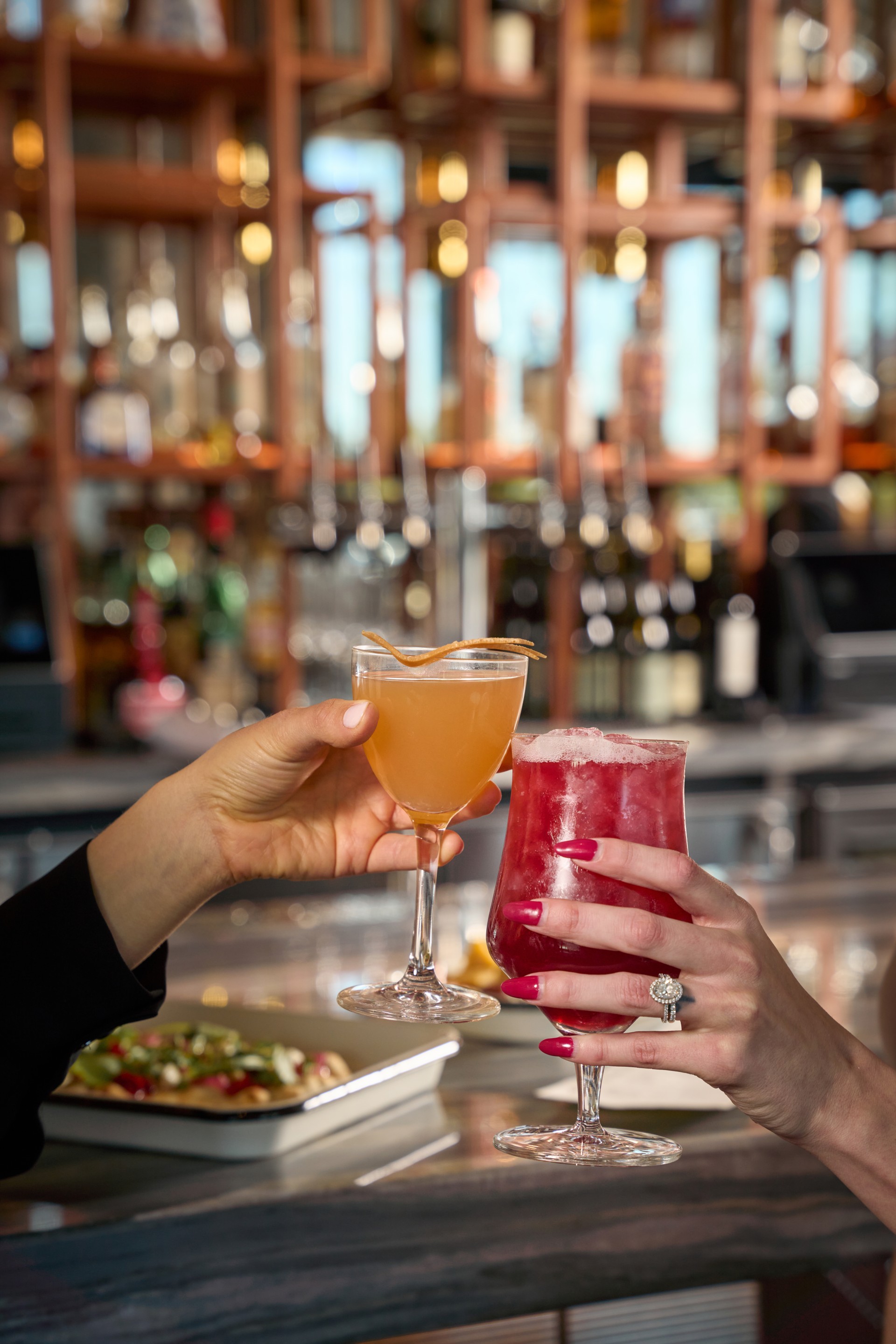 a pair of hands holding drinks at the Keepers Bar