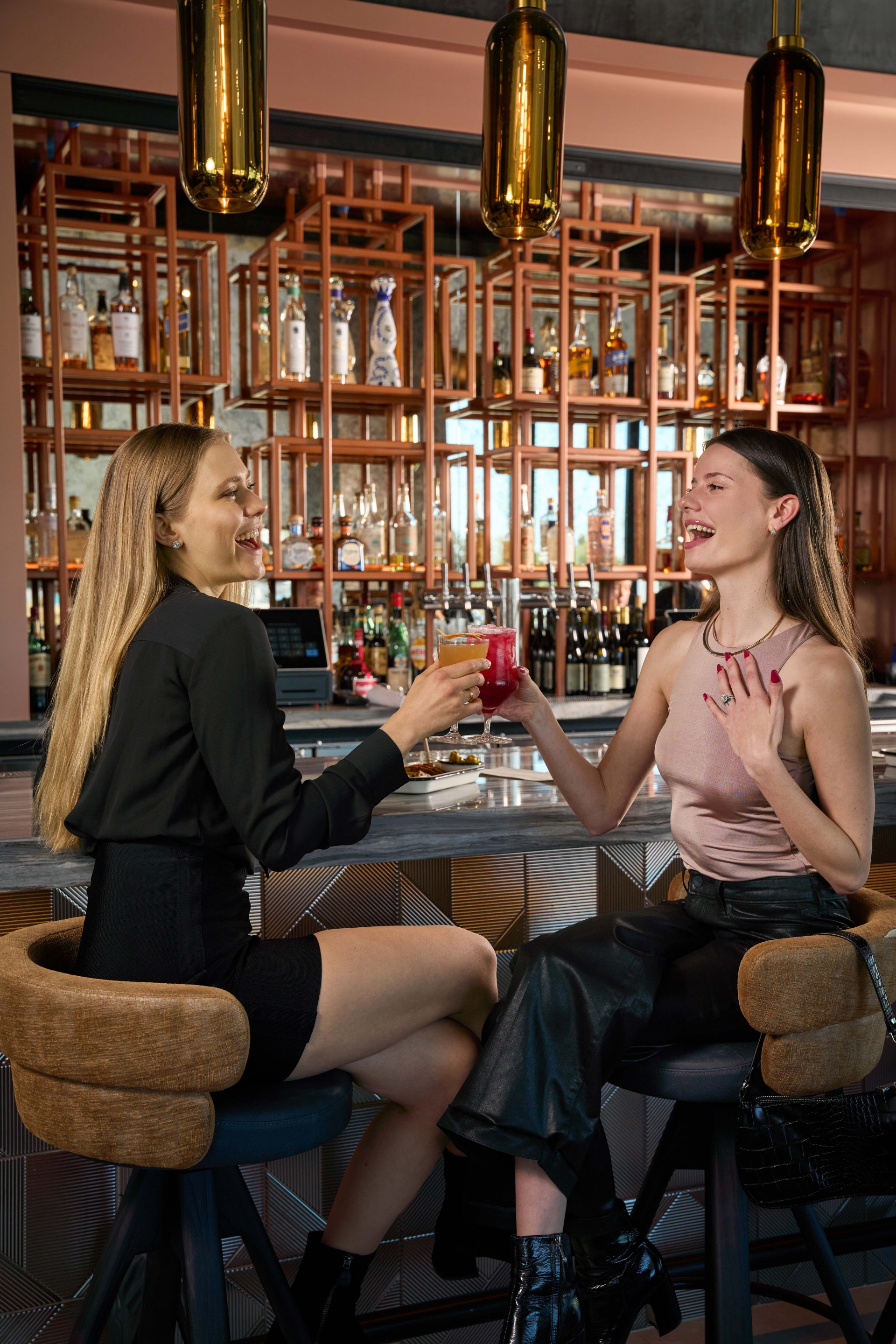 two women sitting at a bar with drinks