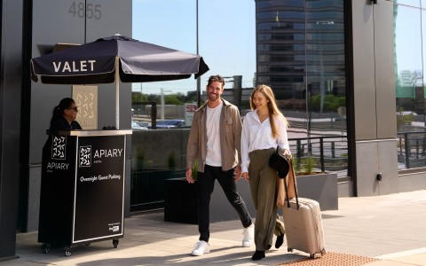 a man and woman walking on a sidewalk with luggage