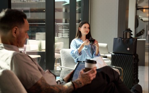 a woman holding a cup of coffee and a man sitting in a chair