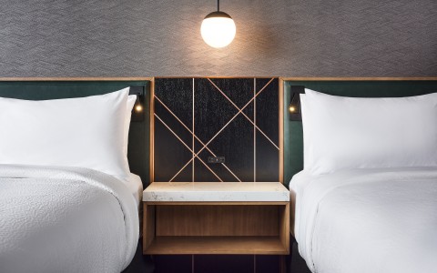 a two beds with white pillows and a light bulb above them