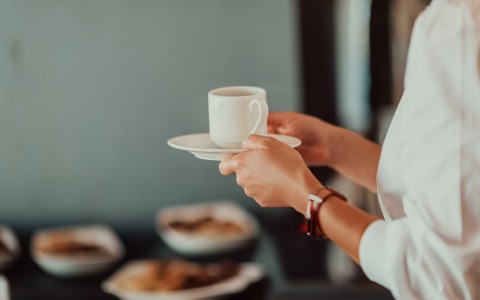 a person holding a cup and saucer