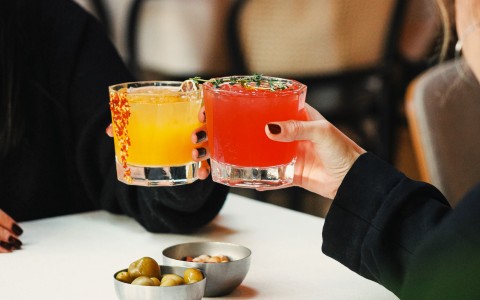 a pair of hands holding glasses with drinks