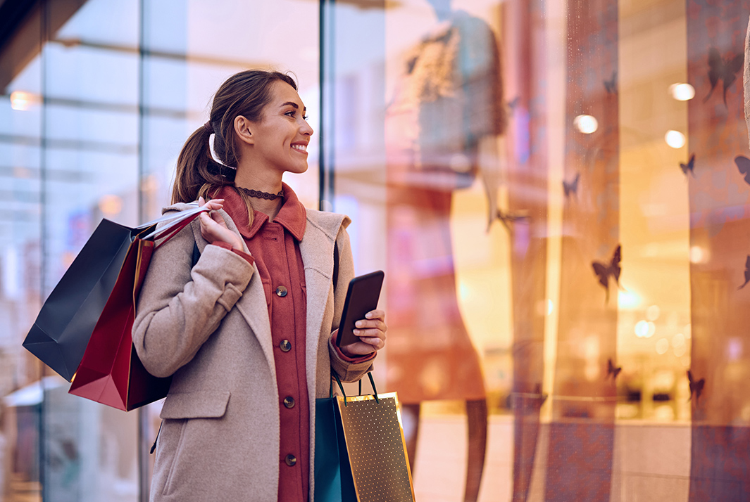 a woman holding shopping bags and a cell phone