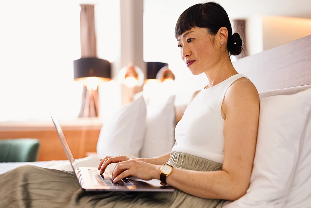a woman sitting on a bed using a laptop