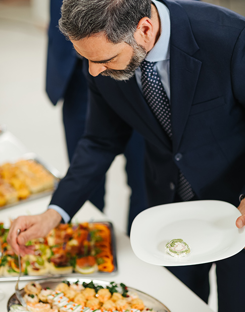 a man in a suit holding a plate with food on it