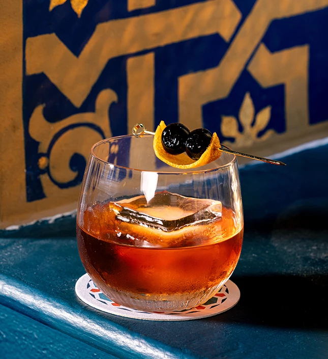 a glass with brown liquid and a slice of lemon on it