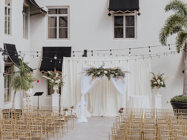 a wedding ceremony with chairs and a white cloth arch