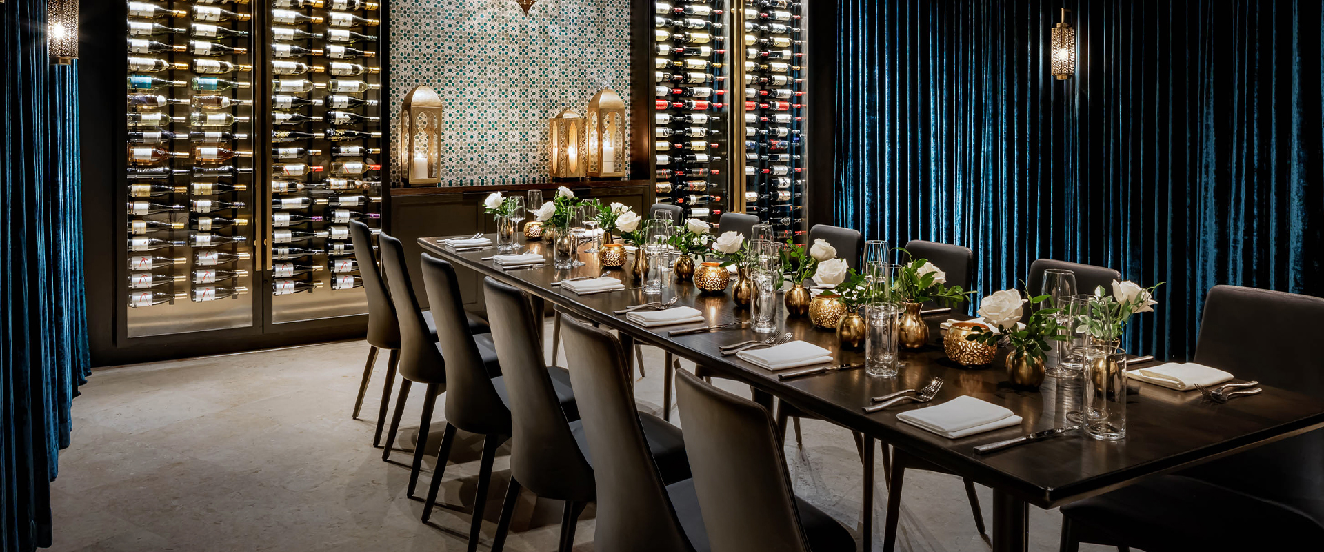 a long table with wine bottles and flowers
