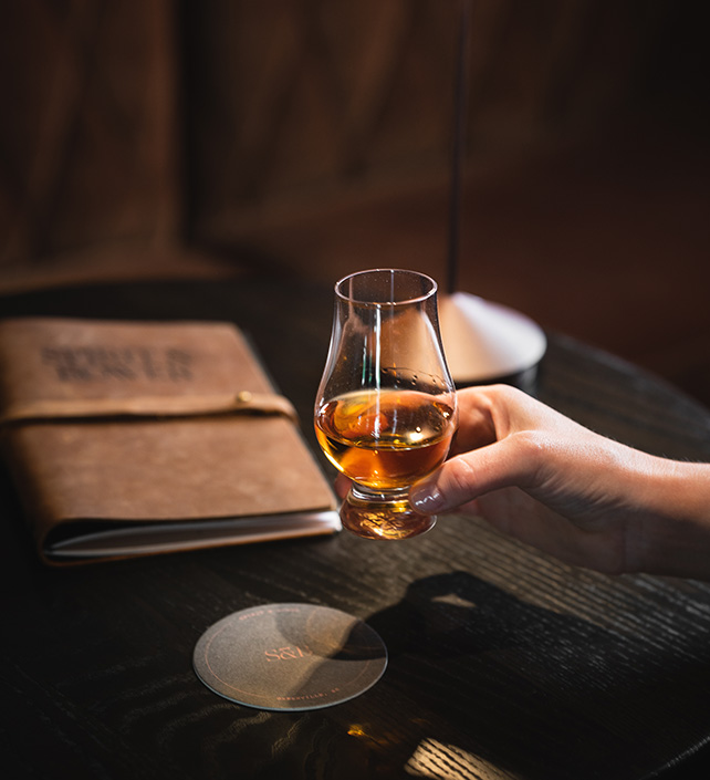 a hand holding a glass of alcohol
