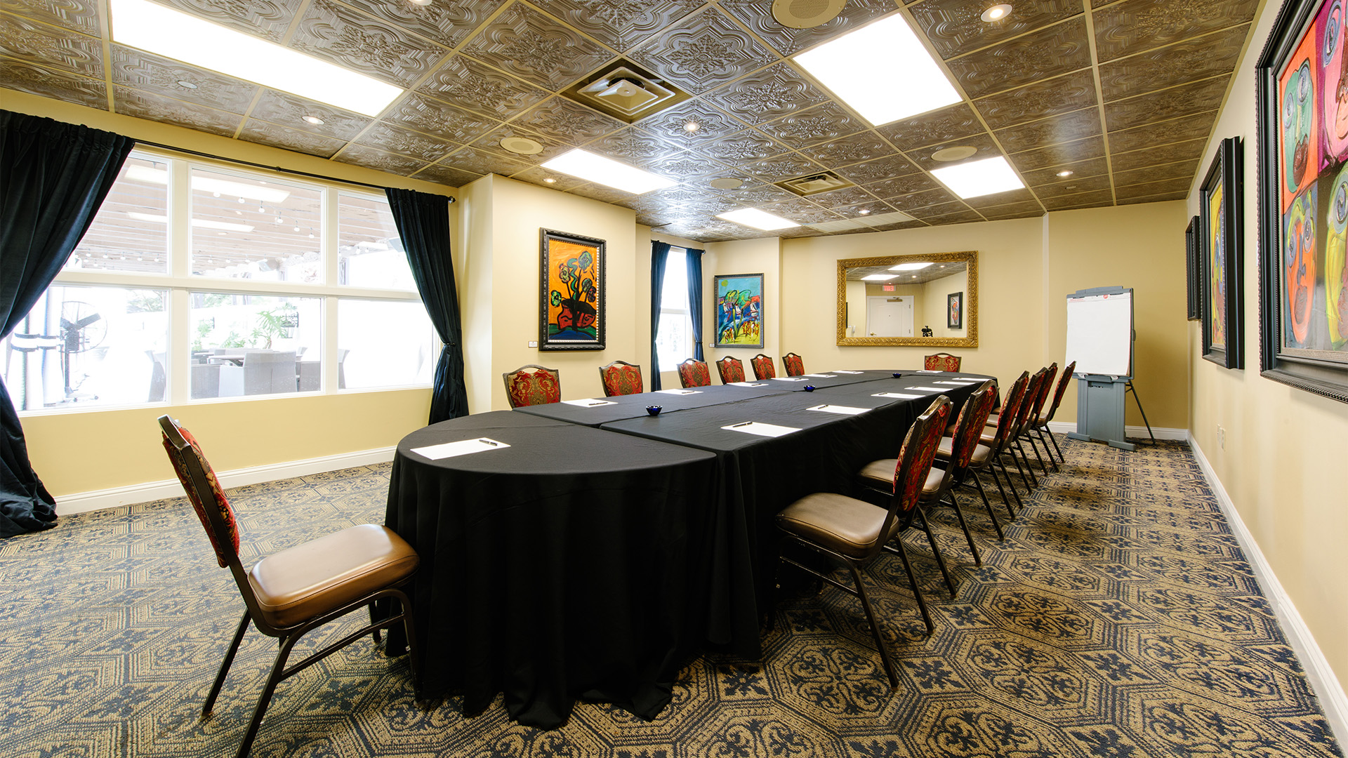 a long table with chairs in a room with a mirror and a black tablecloth