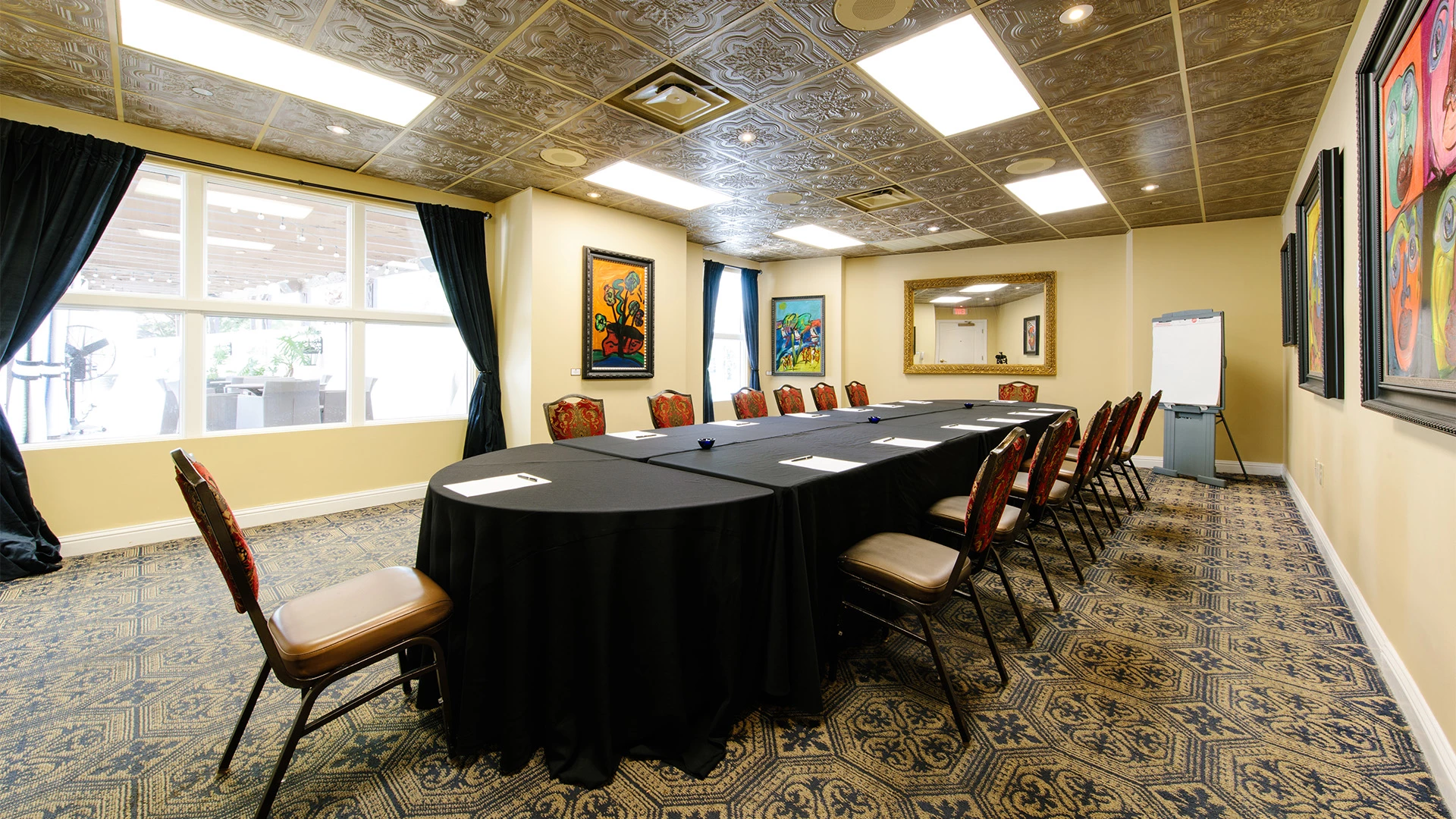a long table with chairs in a room with a mirror and a black tablecloth