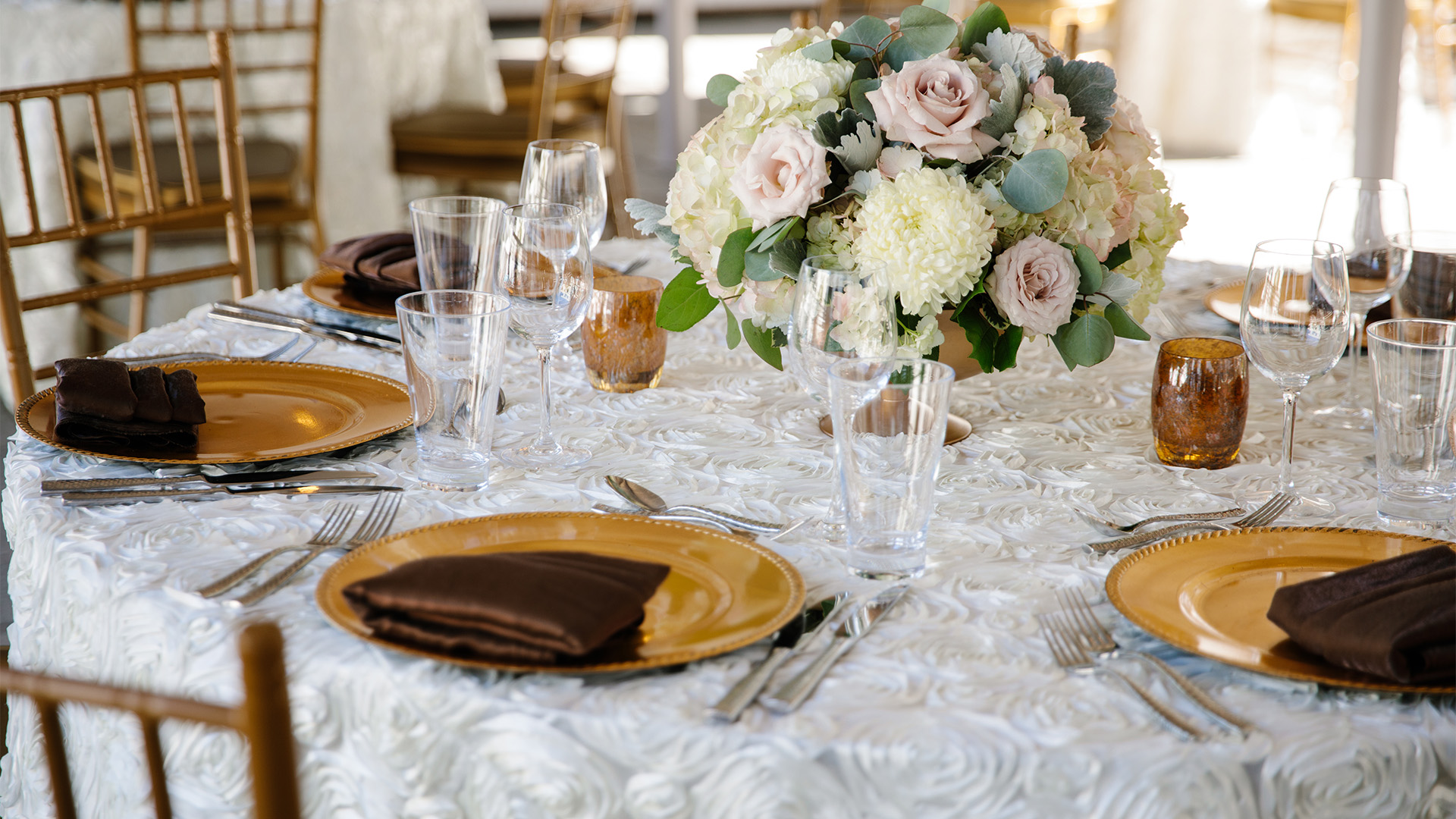 a table set with plates and glasses and a bouquet of flowers